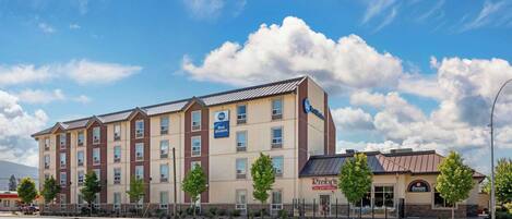 A multi-story hotel with a modern design, featuring a Best Western sign, a Rick's All Day Cafe, and a Famous Pit Stop.