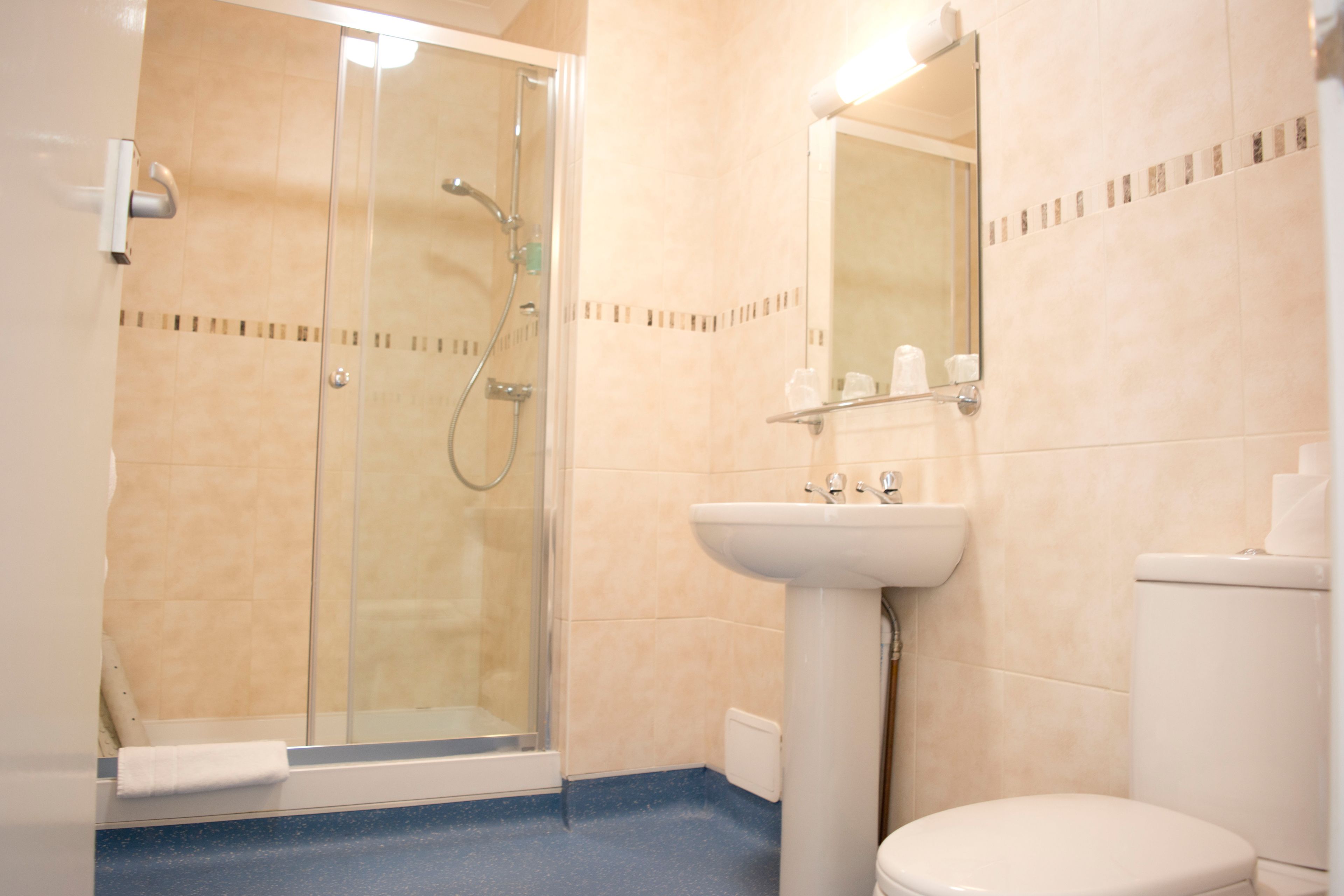 A bathroom with a glass shower enclosure, a pedestal sink, and a toilet.