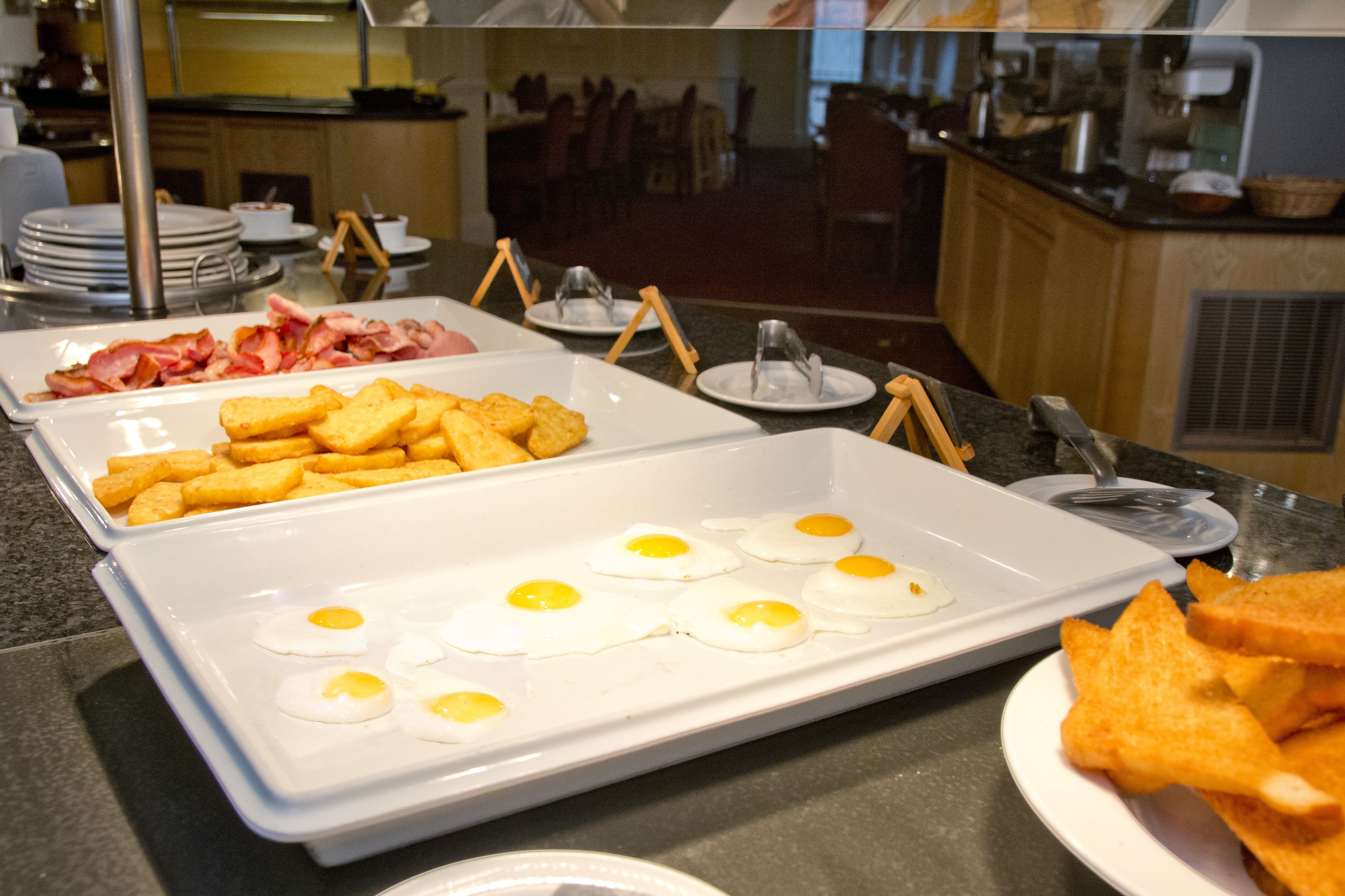 A buffet with various breakfast items including bacon, eggs, and toast.