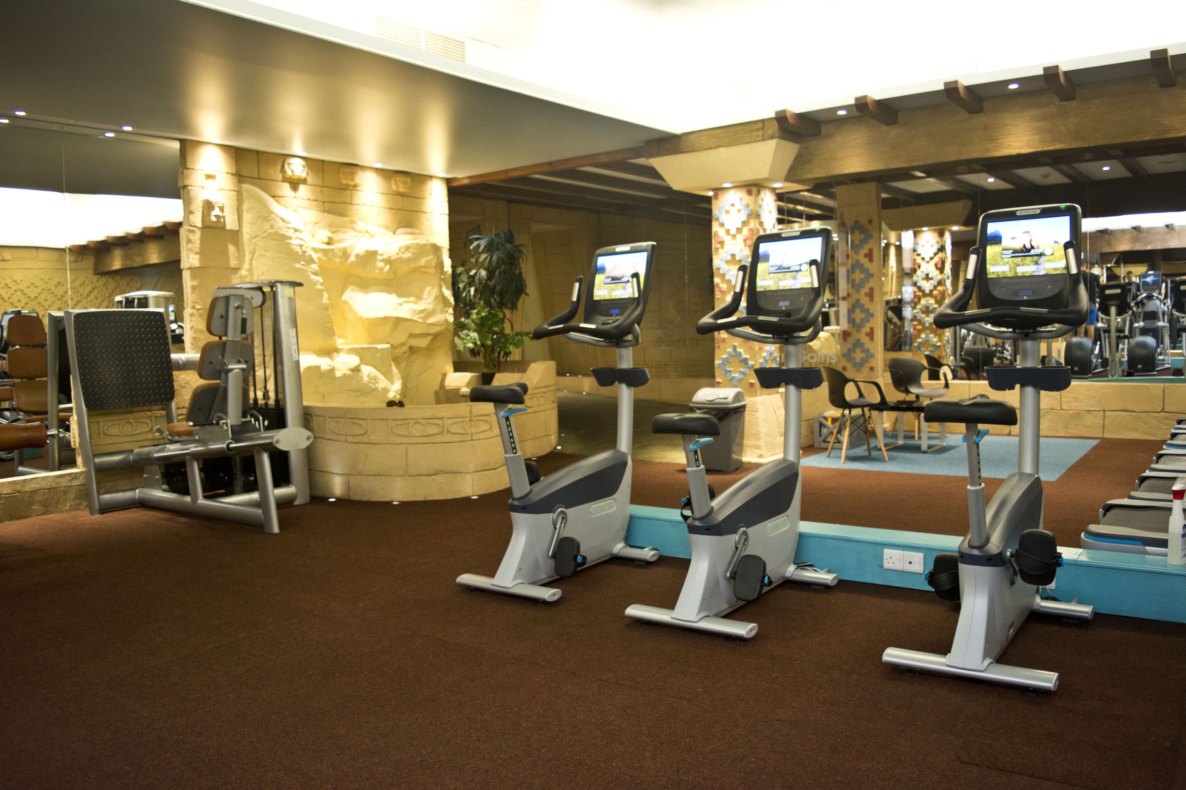 A gym with stationary bikes, weight machines, and a large mirror.