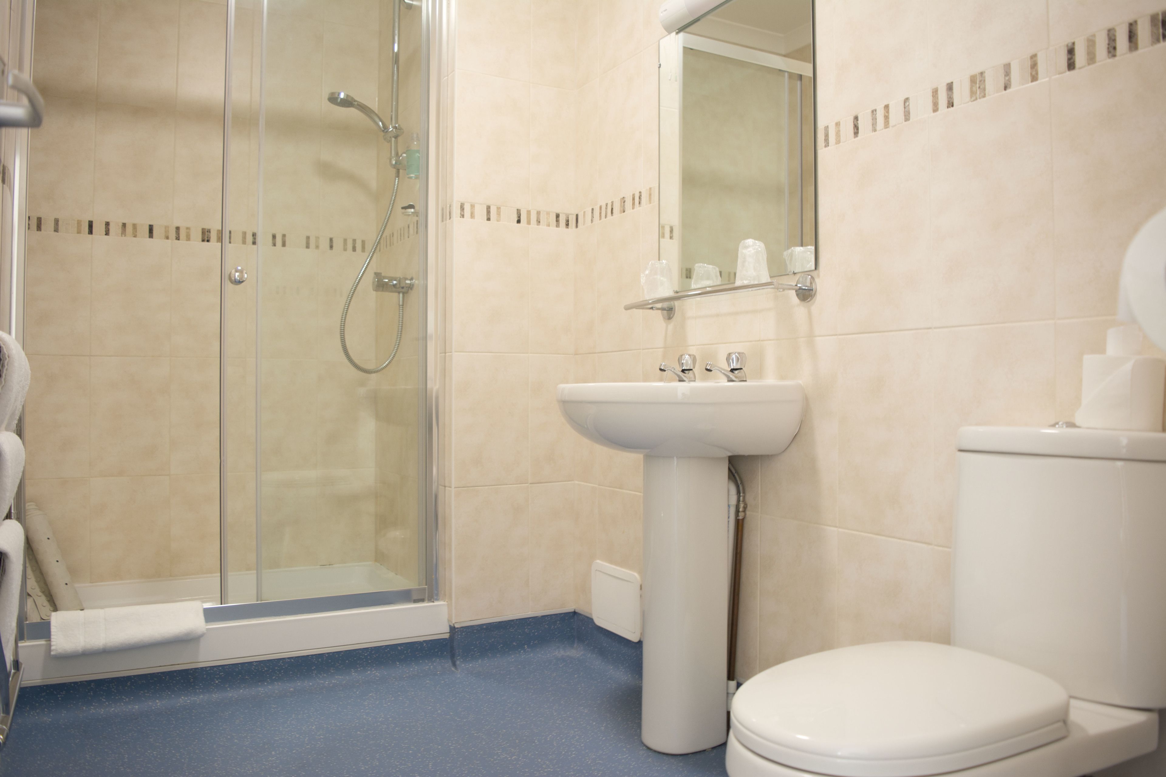 Un baño con cabina de ducha de vidrio, un lavabo con espejo y un inodoro.