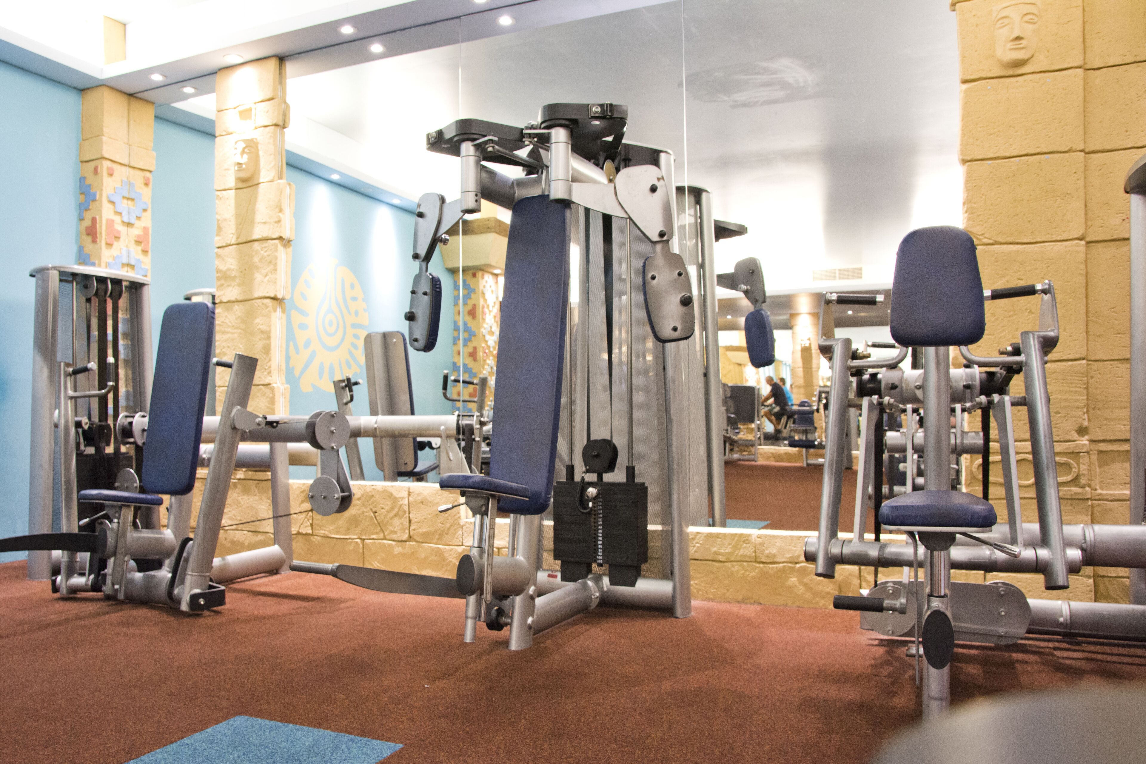 Ein Fitnessraum mit verschiedenen Trainingsgeräten und einer blauen Matte auf dem Boden.