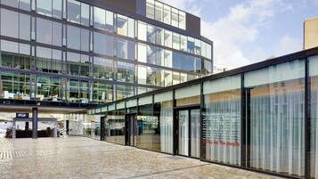 A modern building with large glass windows and a brick-paved entrance area.