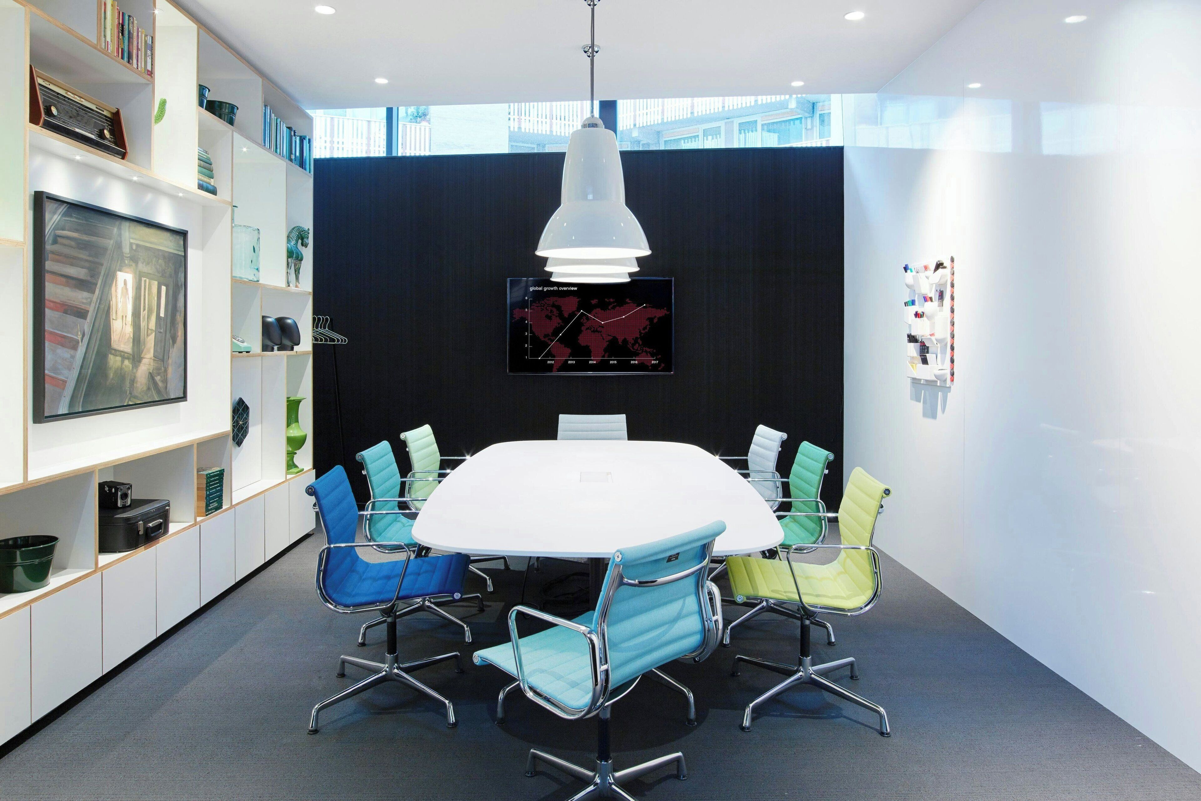 Una sala de reuniones moderna con una mesa redonda, sillas coloridas, un gran globo terráqueo y una estantería.