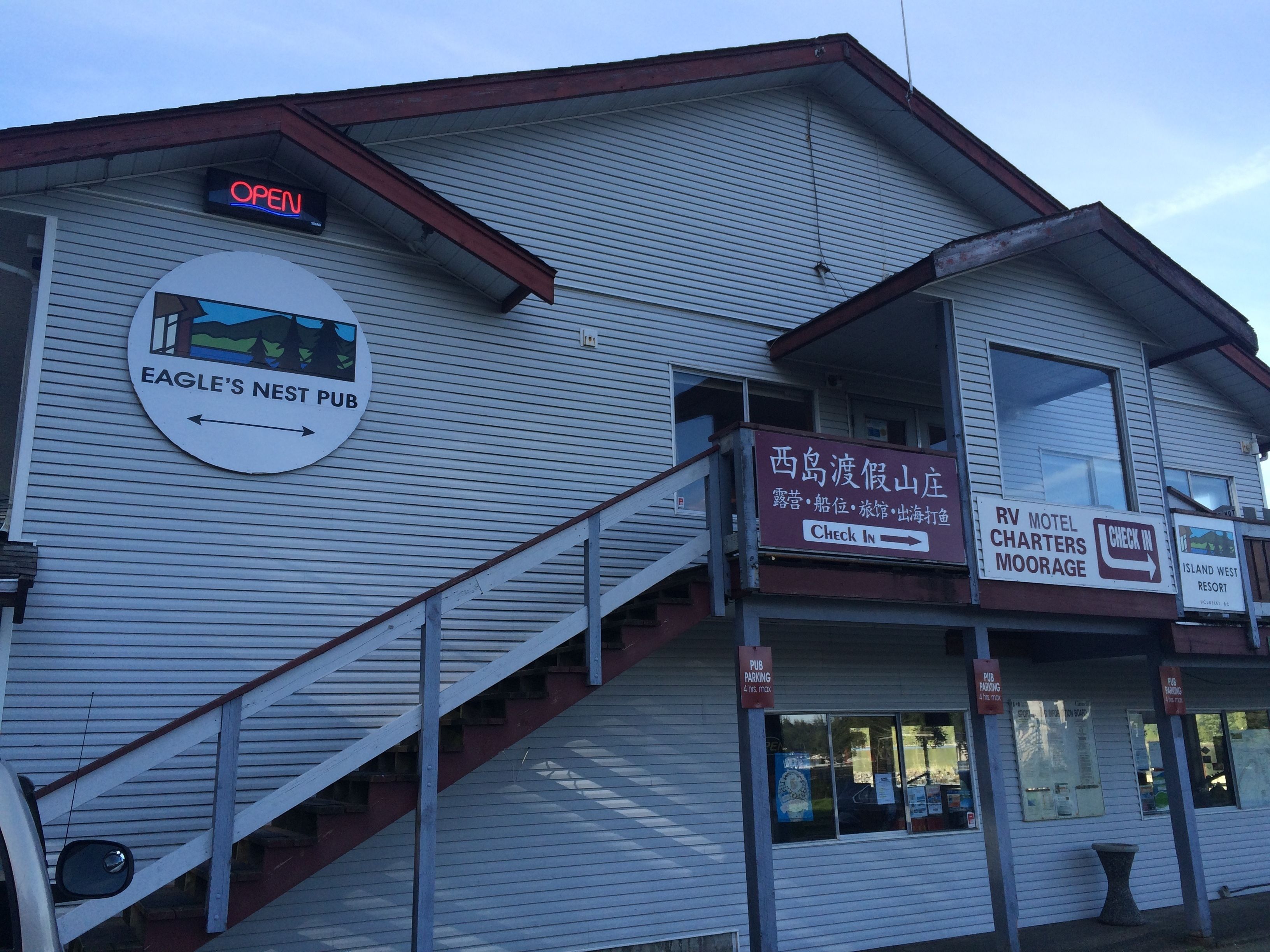 Een gebouw met een bord voor Eagle's Nest Pub, een incheckbord voor RV Motel Charters Moorage, en een bord voor Island West Resort.