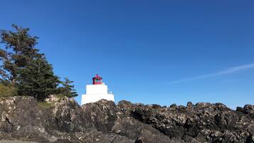 Un faro sobre un promontorio rocoso bajo un cielo azul despejado.