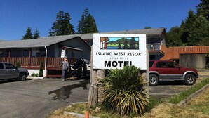 A motel sign for Island West Resort in Ucluelet, BC, with a vehicle parked in front.