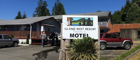 A motel sign for Island West Resort in Ucluelet, BC, with a vehicle parked in front.