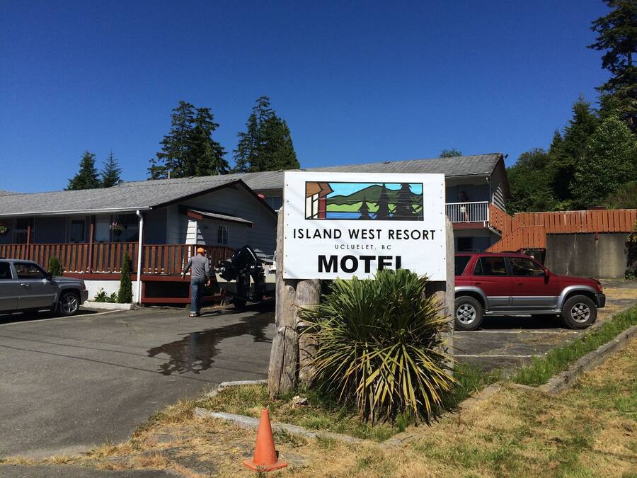 Letrero de motel del Island West Resort en Ucluelet, BC, con un vehículo estacionado al frente.