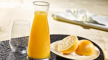 Un vaso de jugo de naranja, un vaso de agua y dos mitades de naranja sobre una mesa.