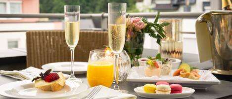 A breakfast setting with a glass of orange juice, a dessert with a strawberry, a glass of champagne, and macarons on a tray.
