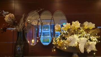 Une composition décorative comprenant un miroir et des fleurs, une vue d'un bâtiment avec une enseigne, et le reflet d'une personne.