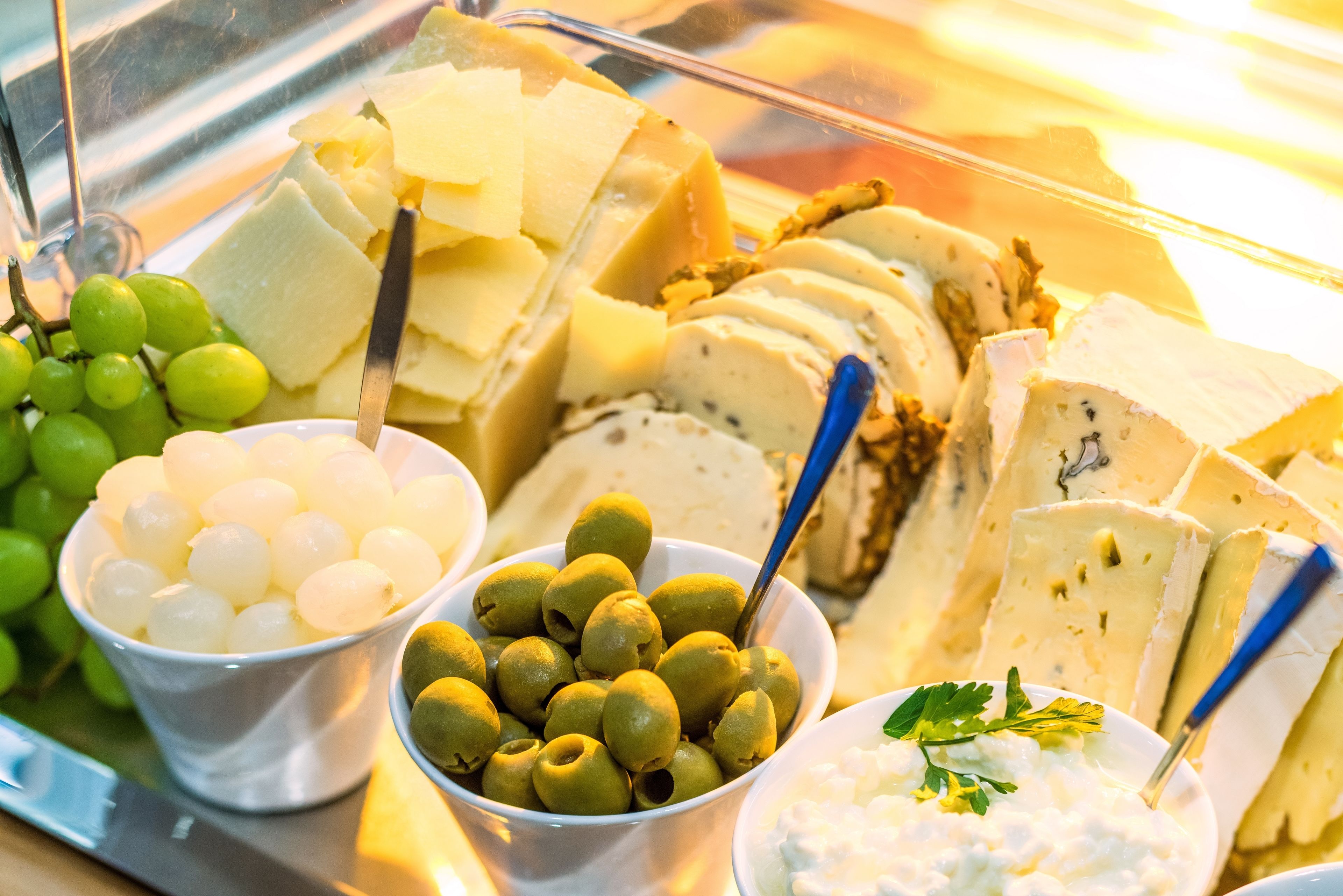 Une présentation de fromages et d’olives, avec différents types de fromages et d’olives disposés dans des bols.