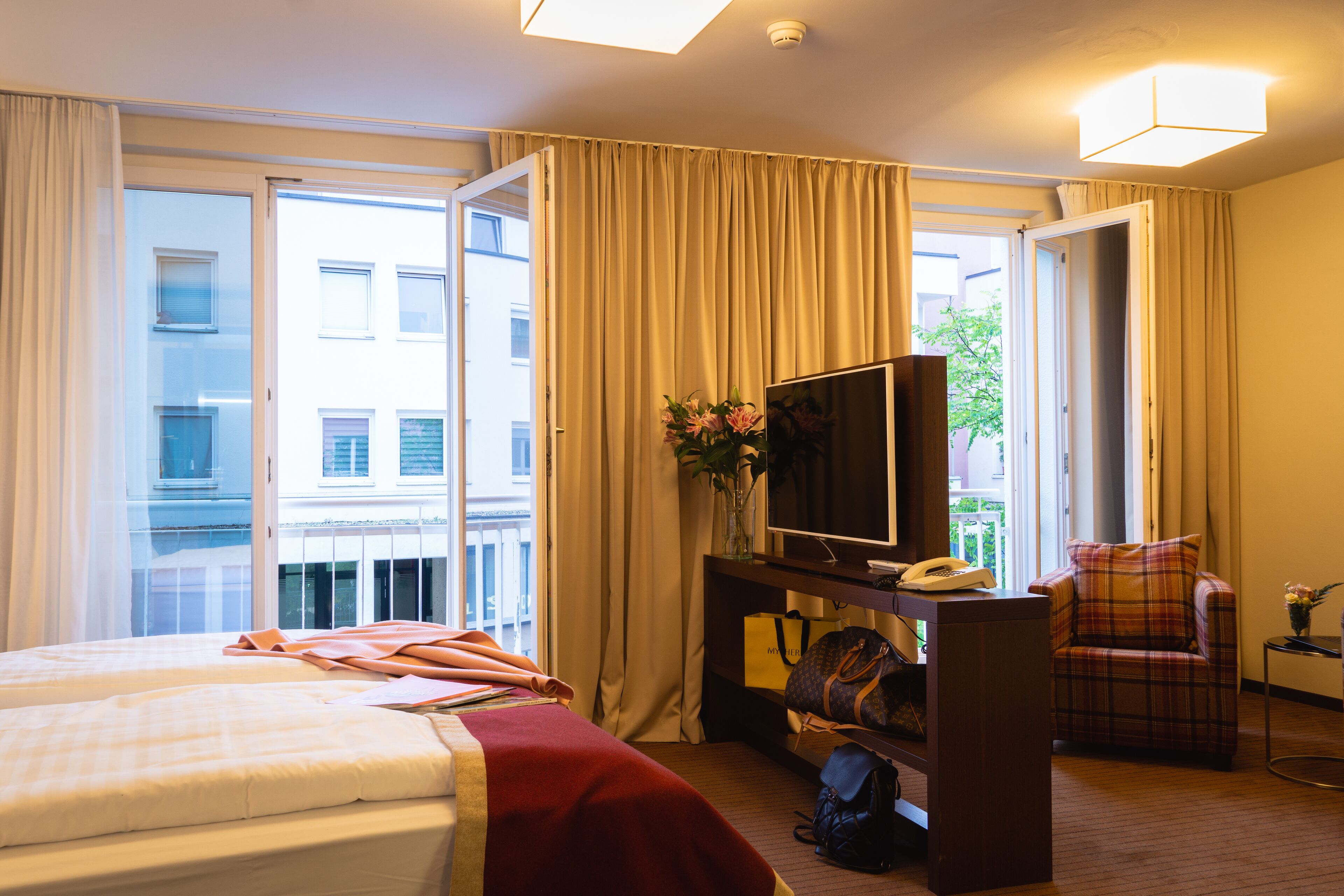 Une chambre d’hôtel comprenant un lit, un bureau avec un téléphone, une chaise et un téléviseur.