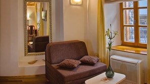 A cozy room with a brown sofa, a small table with a vase, a mirror, and a window with curtains. - Hotel Monika (Trogir)