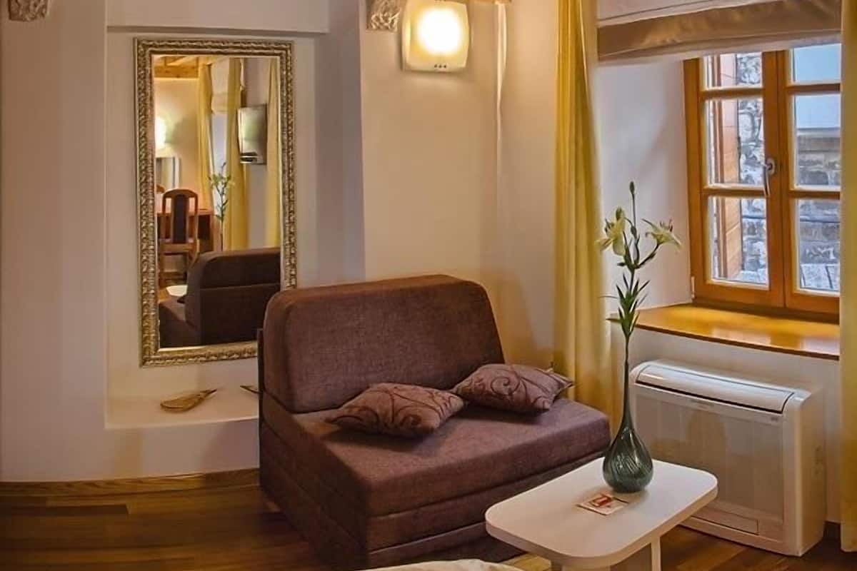 A cozy room with a brown sofa, a small table with a vase, a mirror, and a window with curtains.