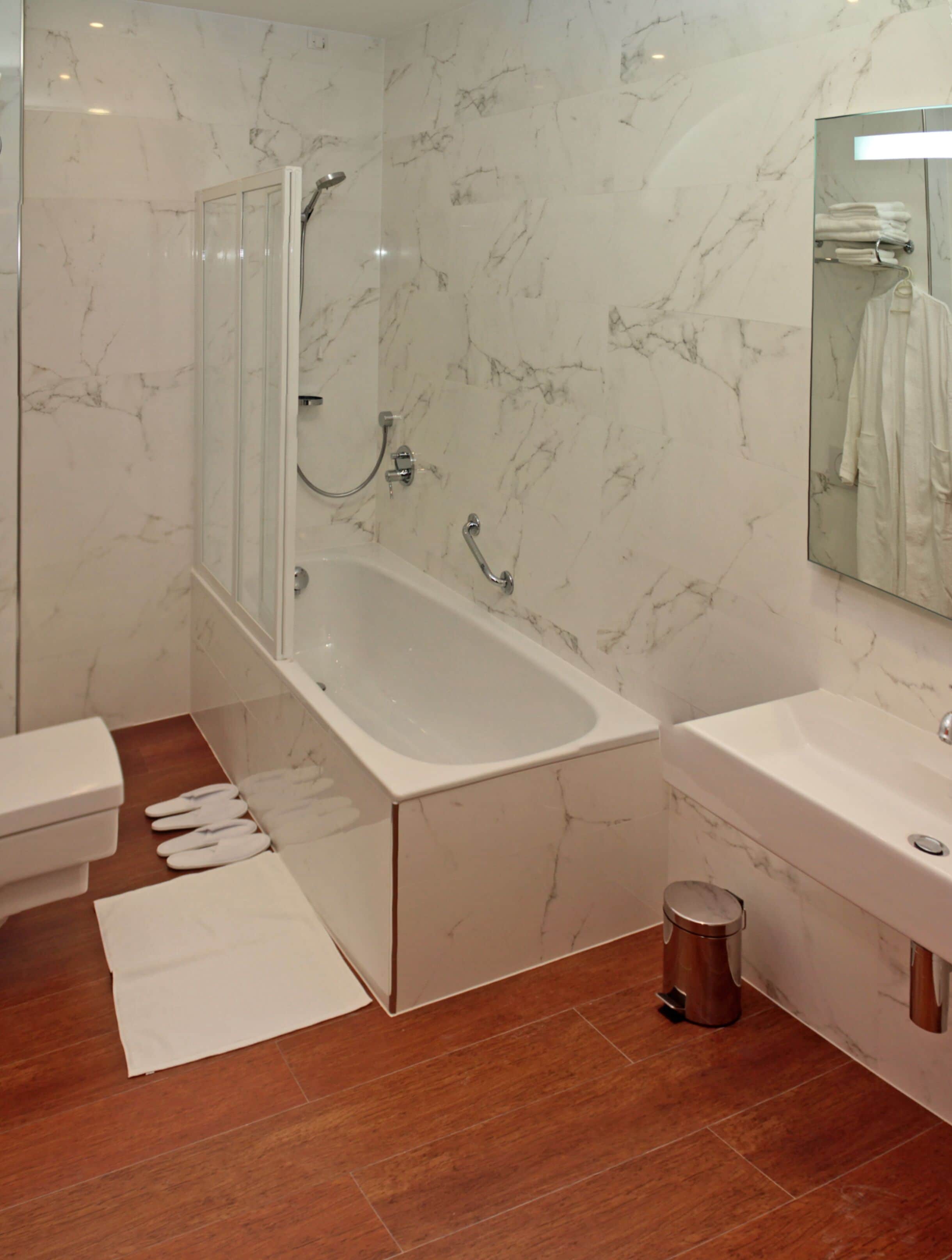 Une salle de bain moderne avec un mur en marbre, une baignoire, des toilettes et un lavabo.