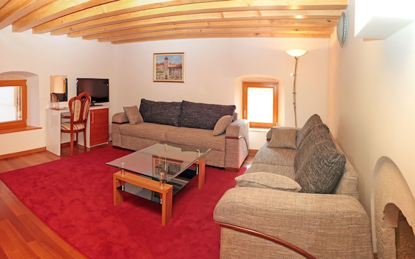 A living room with a sofa, armchair, TV, and a red carpet. - Hotel Monika (Trogir)