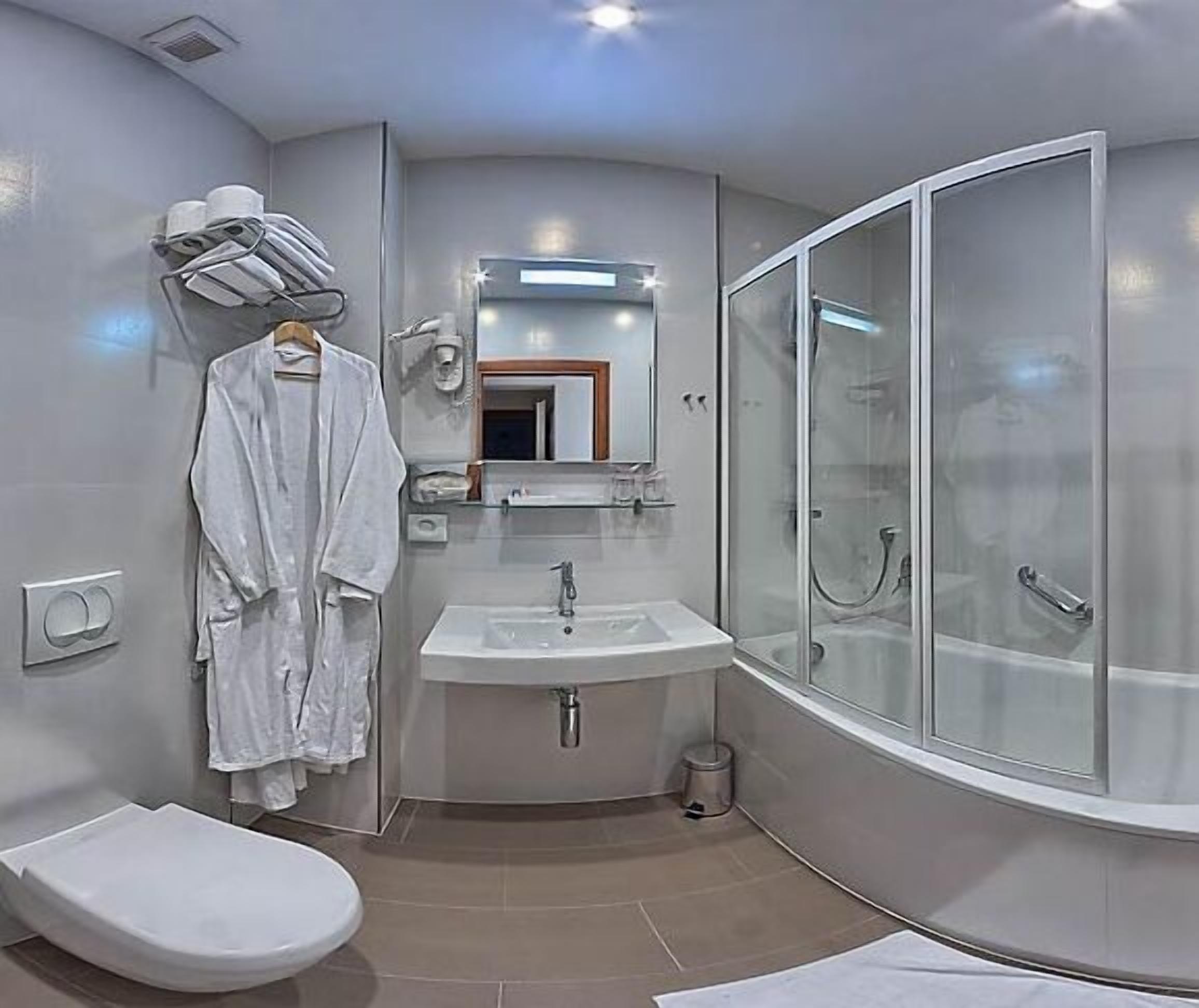 A modern bathroom with a toilet, sink, and glass-enclosed shower.