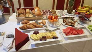 A buffet table with various food items including bread, pastries, fruits, and desserts. - Hotel Monika (Trogir)