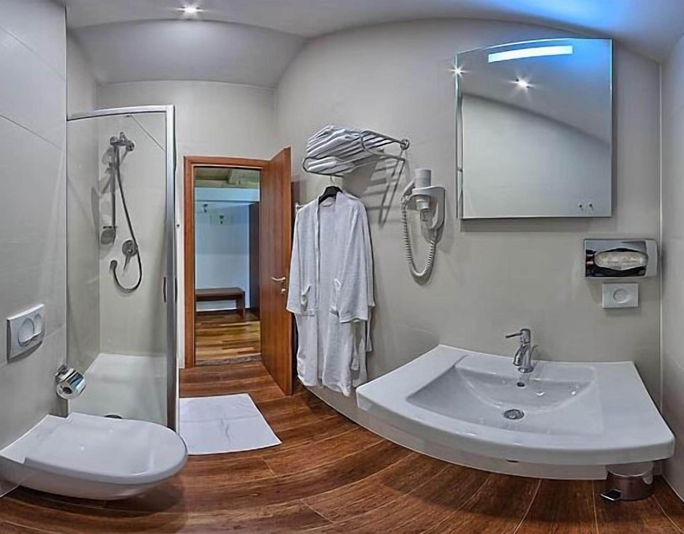 A modern bathroom with a shower, a sink, and a mirror. There is a towel rack with a towel hanging on it.