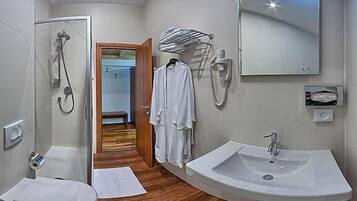 A modern bathroom with a shower, a sink, and a mirror. There is a towel rack with a towel hanging on it.