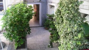 A narrow stone pathway leading to a doorway with a window above. - Hotel Monika (Trogir)
