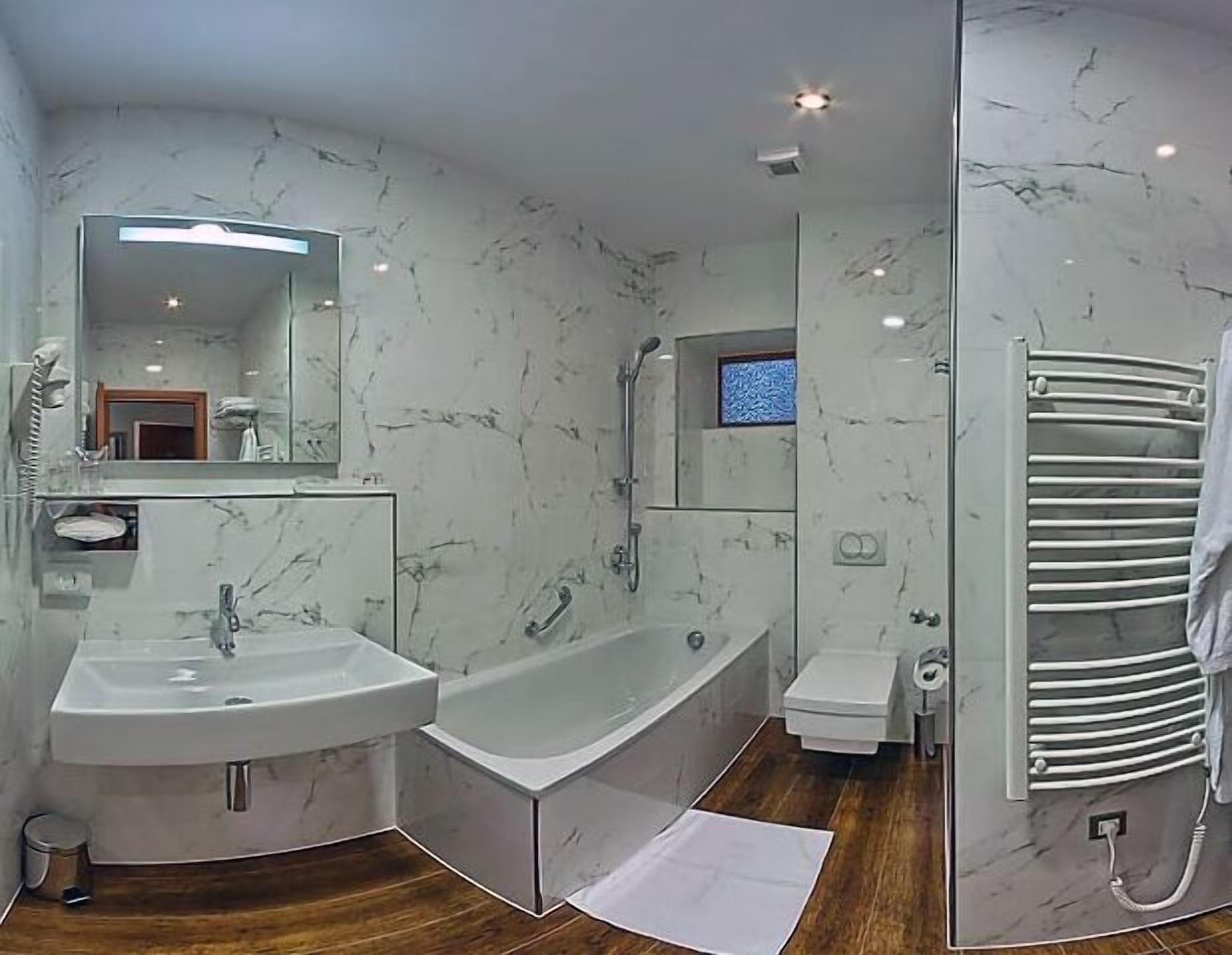 Une salle de bain moderne avec une grande baignoire, deux lavabos, des toilettes et un porte-serviettes.