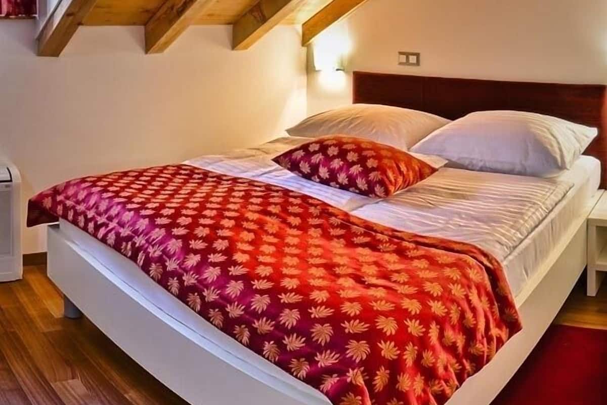 A bedroom with a bed, a nightstand, and a wooden ceiling.