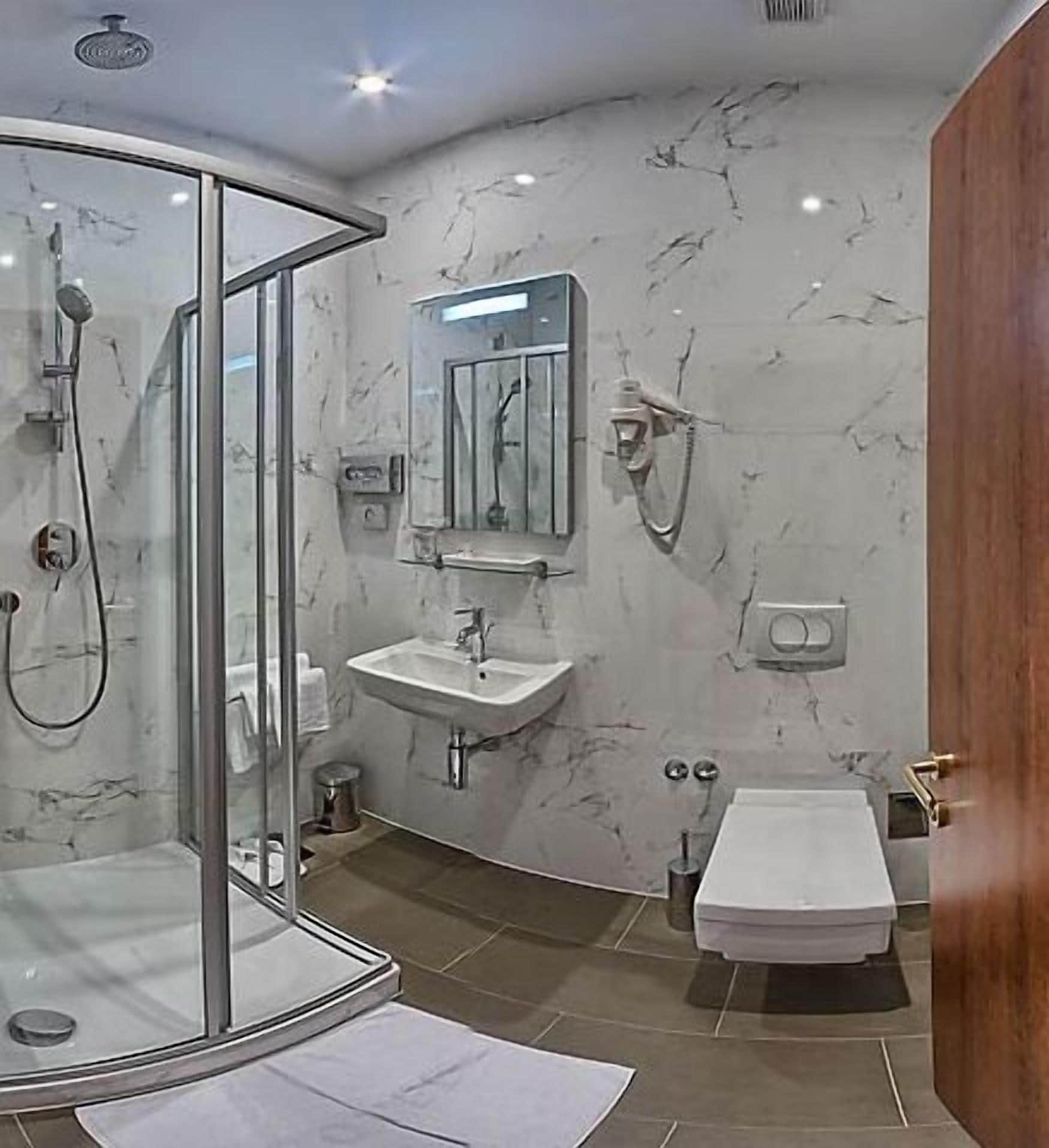 Un baño moderno con cabina de ducha de vidrio, un lavamanos y un inodoro.