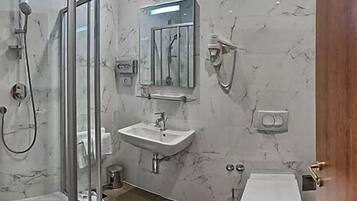 Un baño moderno con cabina de ducha de vidrio, un lavamanos y un inodoro.