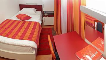 A small, neatly arranged room with a bed, a nightstand, a desk, and a chair.