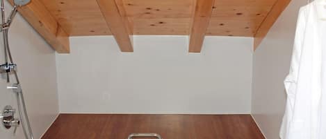 Un baño moderno con techo de madera, bañera, inodoro y ducha.