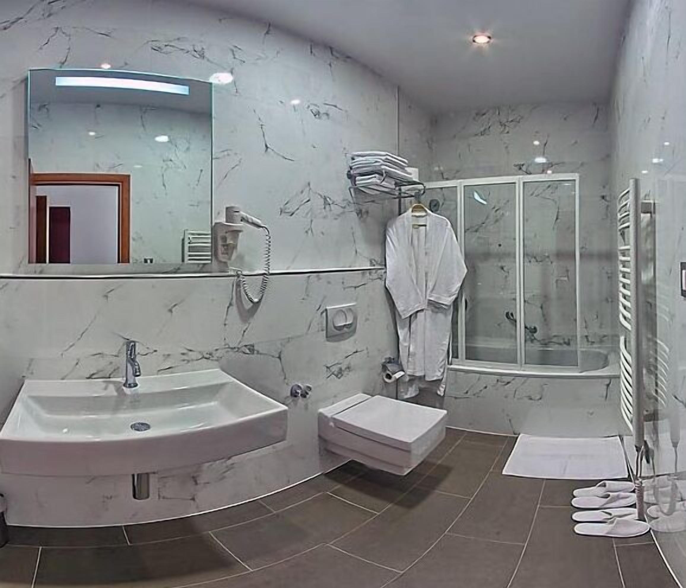 A modern bathroom with two sinks, a shower, and a glass-enclosed shower area.