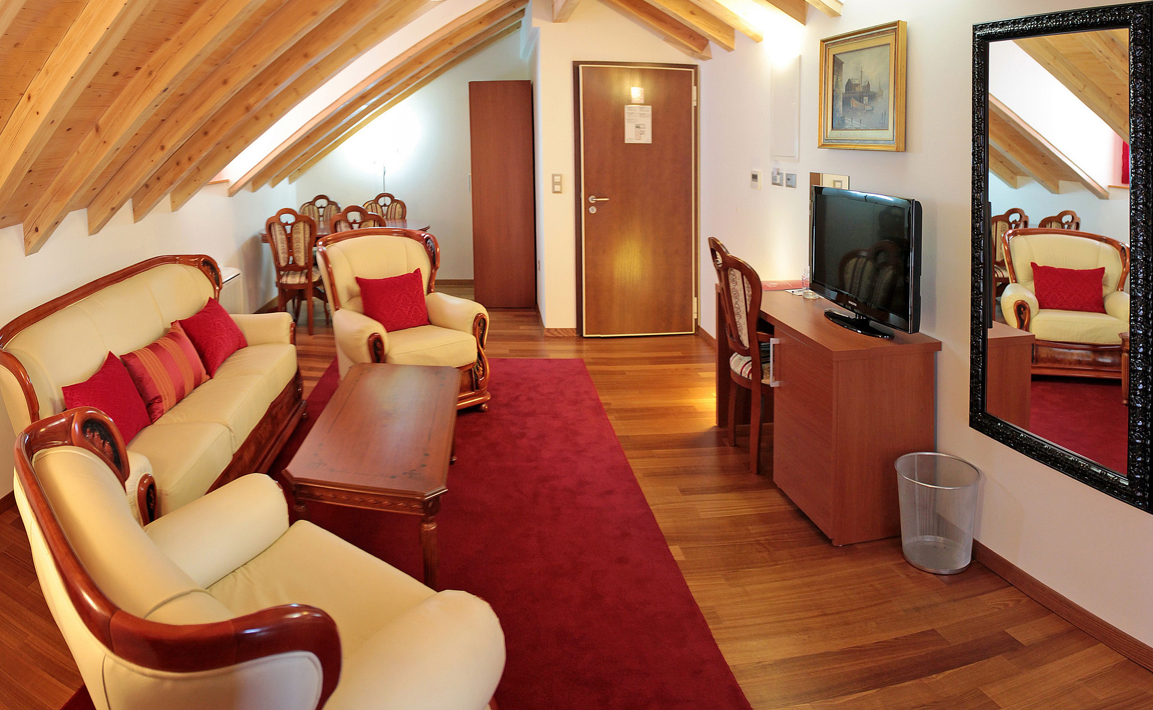 Een gezellige woonkamer met een bank, fauteuils, een salontafel, een televisie en een grote spiegel.
