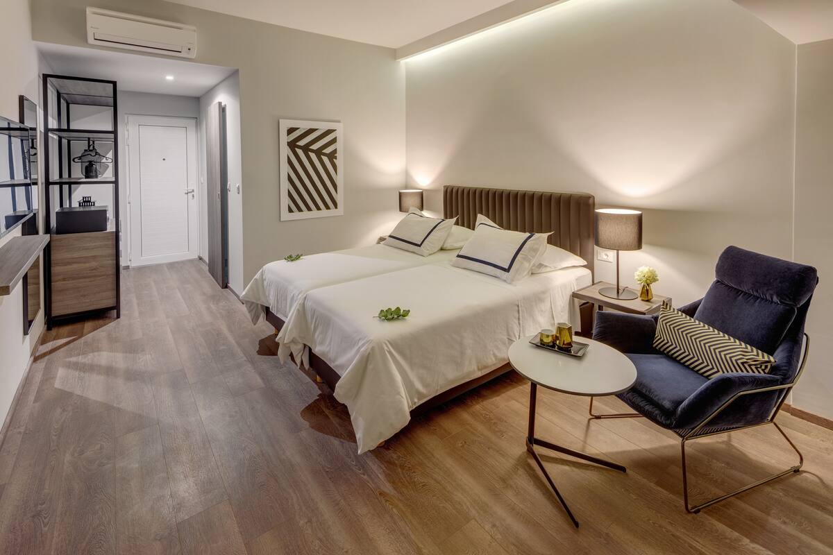 Een hotelkamer met twee bedden, een bureau, een stoel en een kleine tafel.