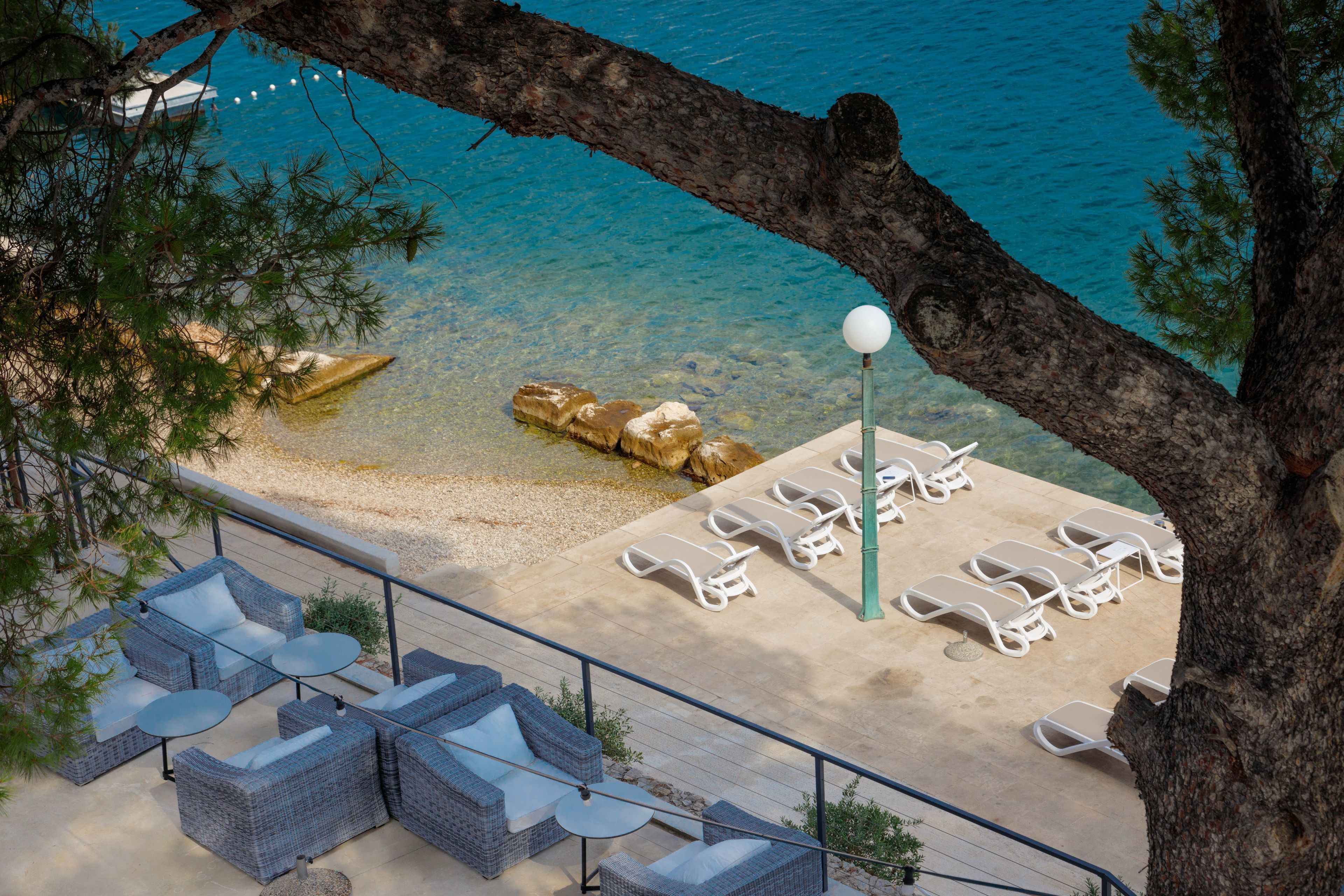 Ein Strandloungebereich mit Korbmöbeln und einem Billardtisch, mit Blick auf das klare, blaue Meer.
