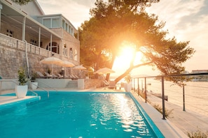 Alberca al aire libre, sombrillas en la alberca y camastros