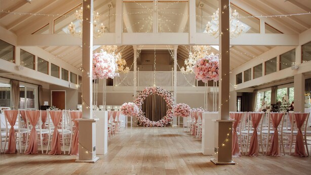 A spacious hall with high ceilings, chandeliers, and floral decorations. -  Marwell Hotel Winchester South (Winchester)