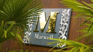 A sign with the letters "IWT" and the word "Marwell" in gold and white, surrounded by green foliage. -  Marwell Hotel Winchester South (Winchester)