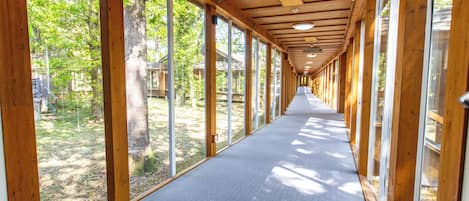 A corridor with wooden beams, large windows, and a carpeted floor.