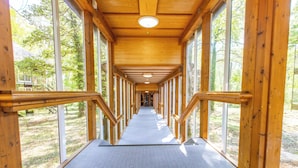 A wooden corridor with large windows, leading to a building entrance. -  Marwell Hotel Winchester South (Winchester)