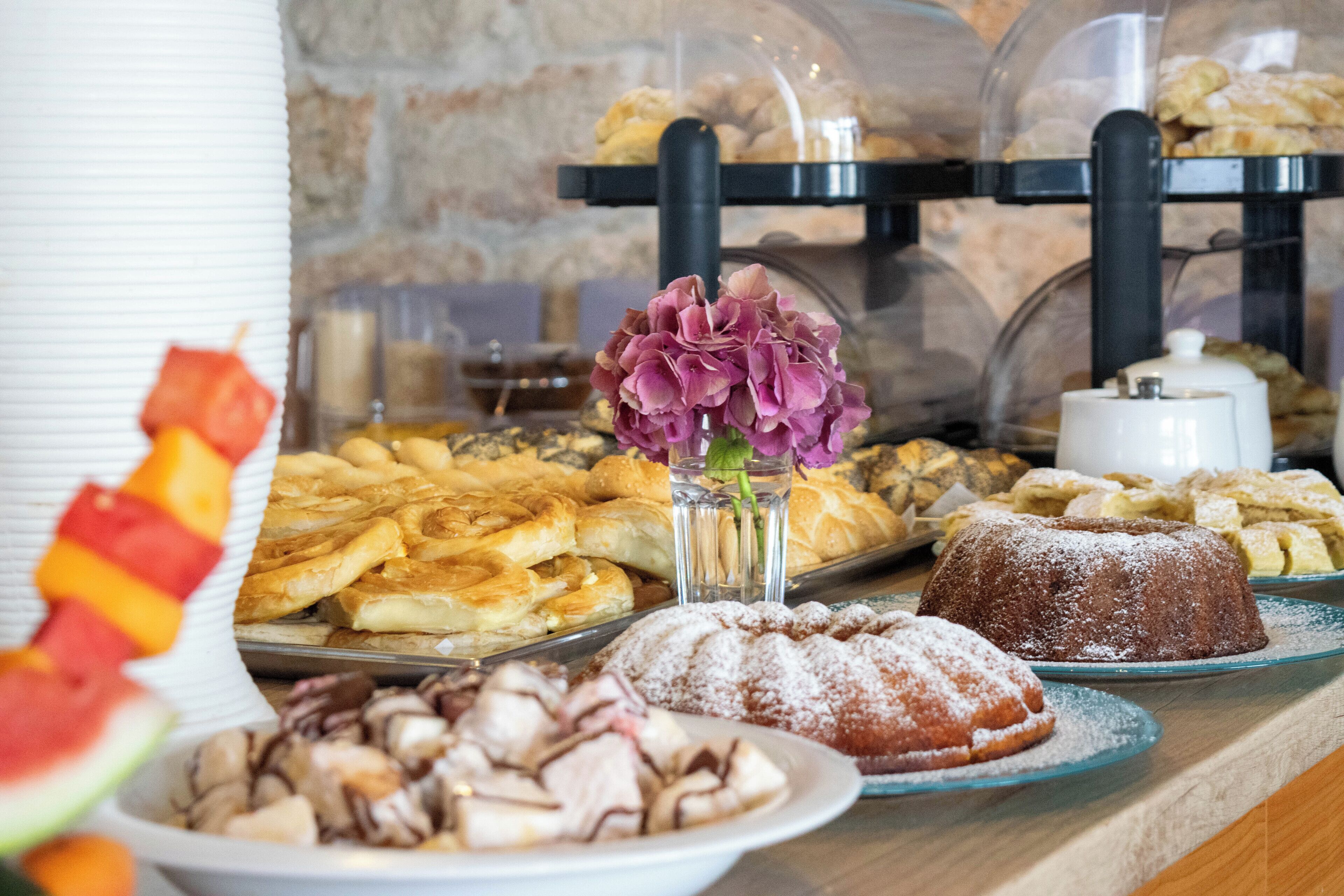 A buffet with various pastries and desserts, including a bundt cake and a plate of sliced fruit.