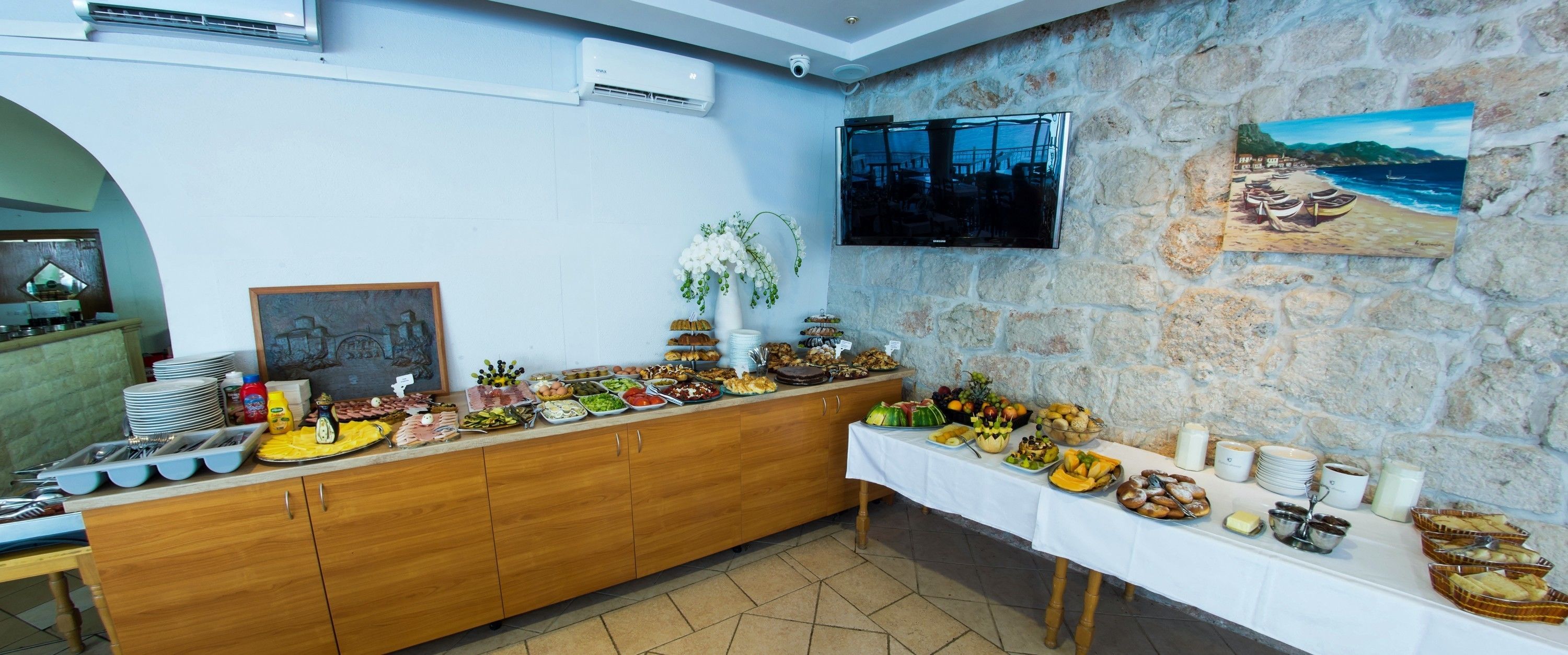A buffet setup with various food items and a television mounted on a stone wall.
