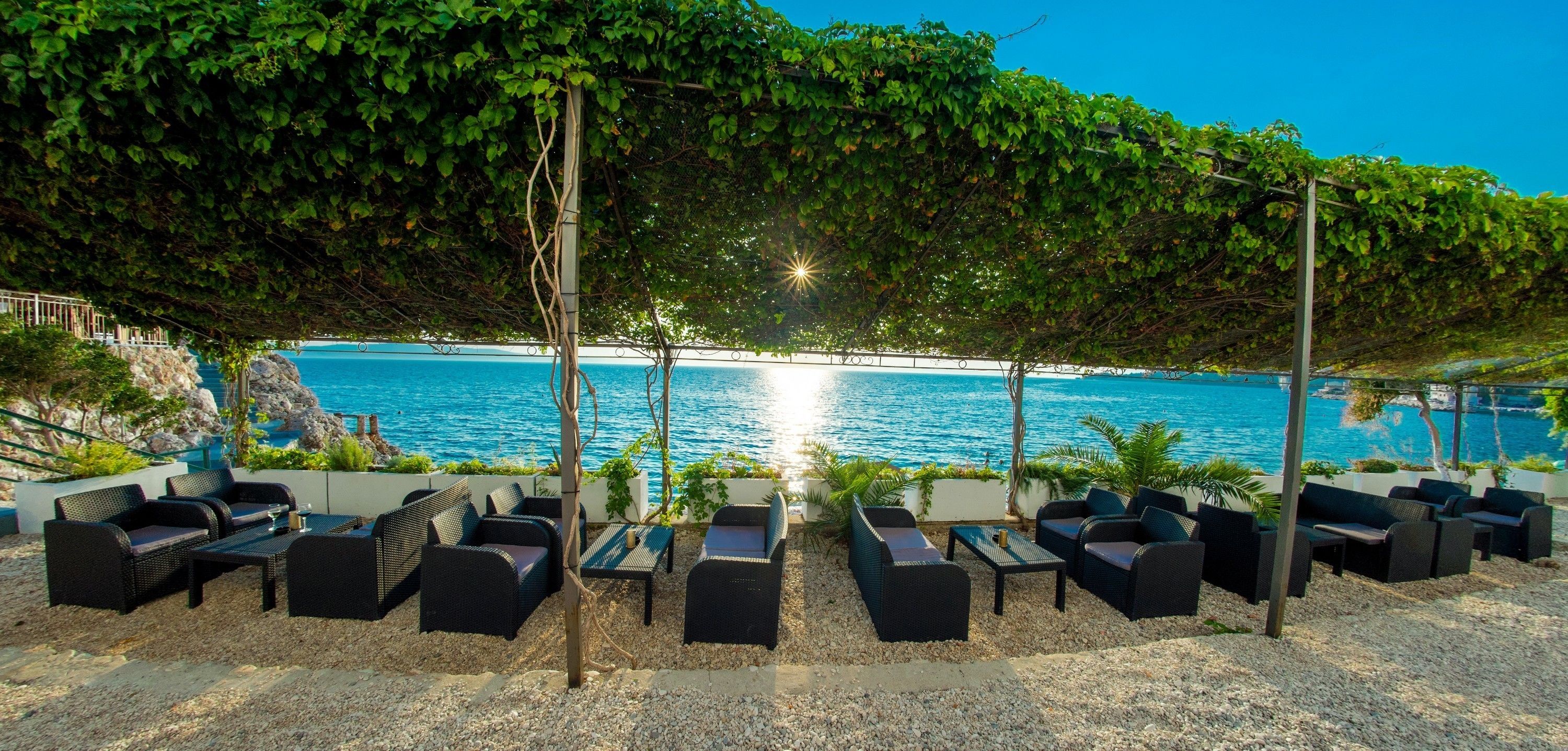 A seaside patio with outdoor seating and a view of the ocean.