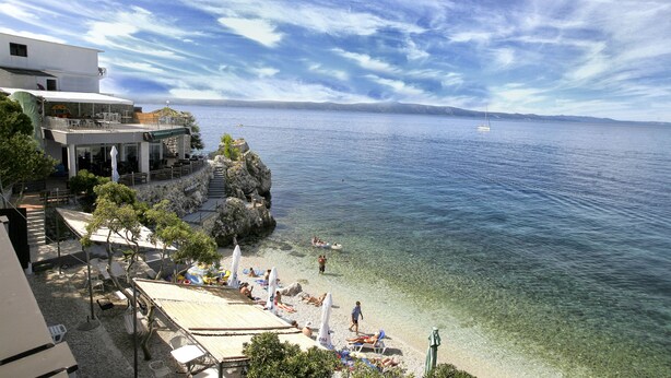 A coastal hotel with clear waters, a beach, and a view of the sea. - Beach Hotel Plaza (Podgora)