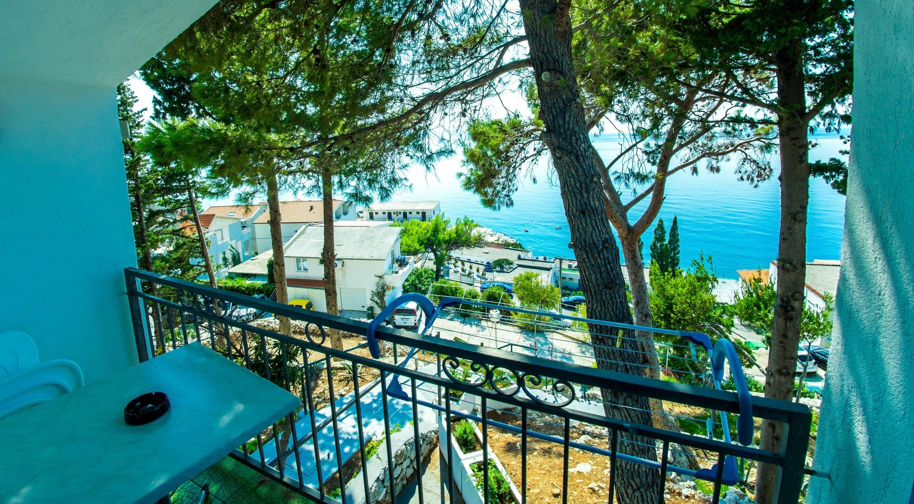 Ein Balkon mit Blick auf eine Küstenstadt, mit Häusern und blauem Meer.
