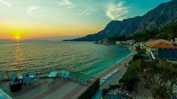 Vista costera con un atardecer, una playa y edificios a lo largo de la orilla.