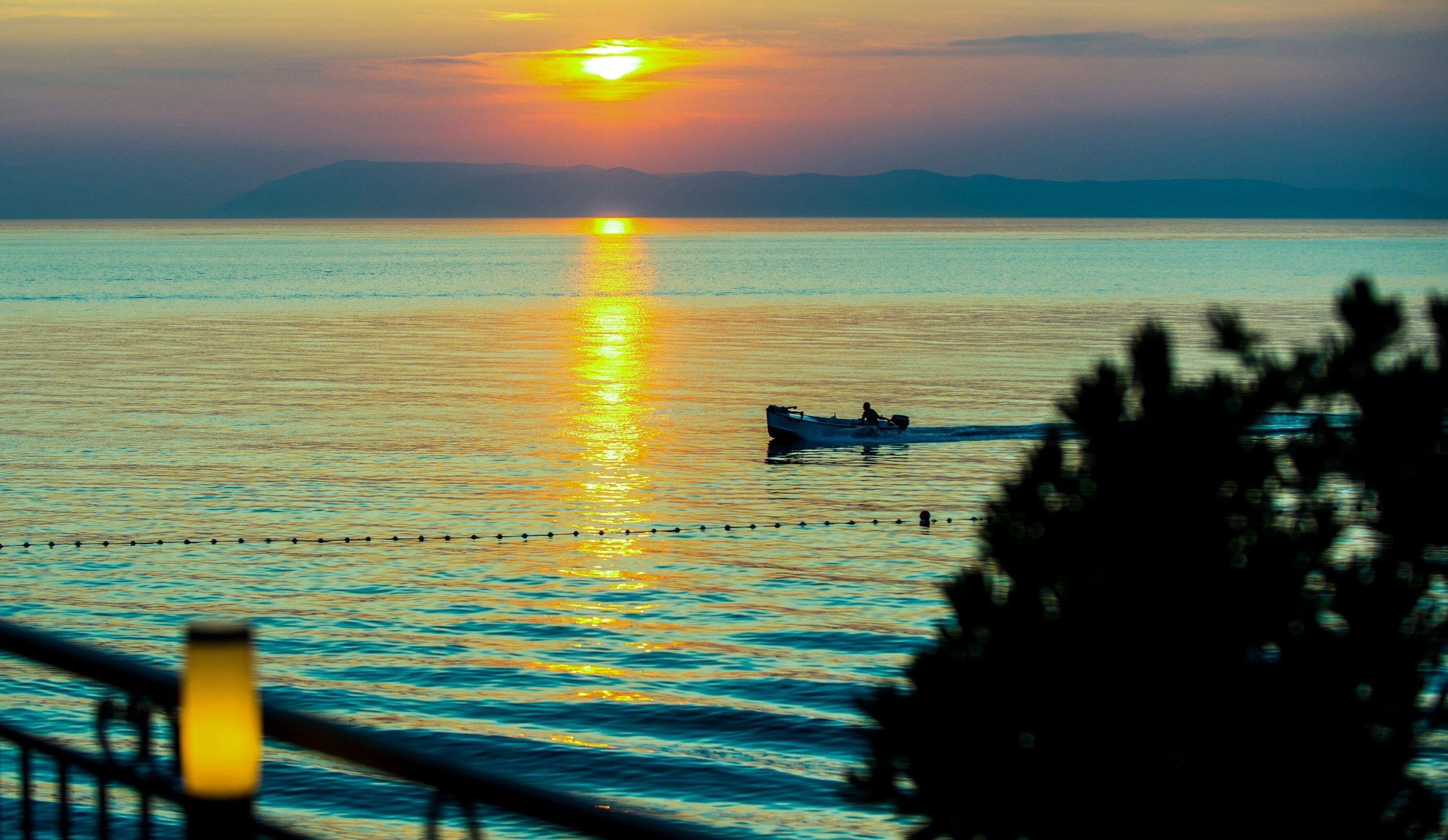 Un barco sobre aguas tranquilas con un atardecer de fondo.