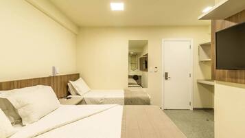 Habitación de hotel con dos camas, un televisor montado en la pared y una puerta que da a un baño.